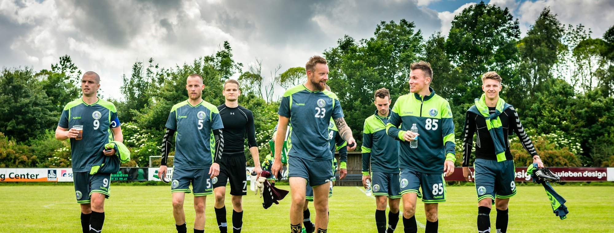 A football team walking out on a grass pitch