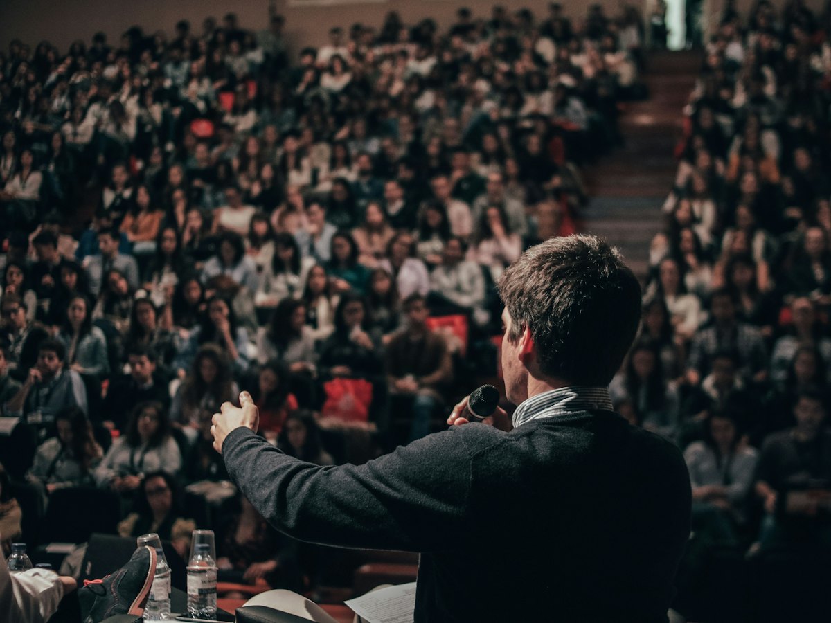A speaker on stage in front of a packed audience